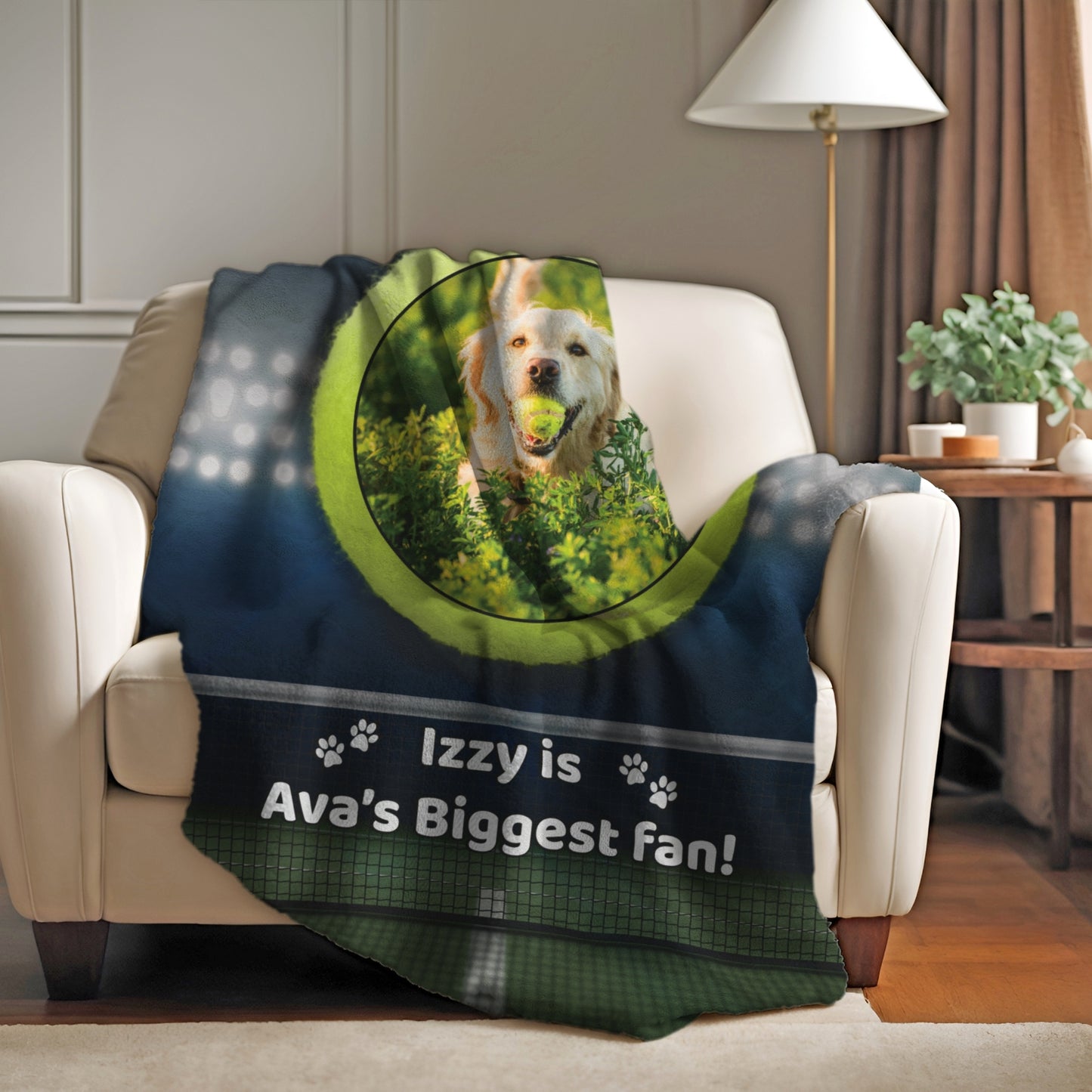 Personalized tennis-themed pet blanket with dog photo and “Izzy is Ava’s Biggest Fan!” text, draped over an armchair in a cozy living room.
