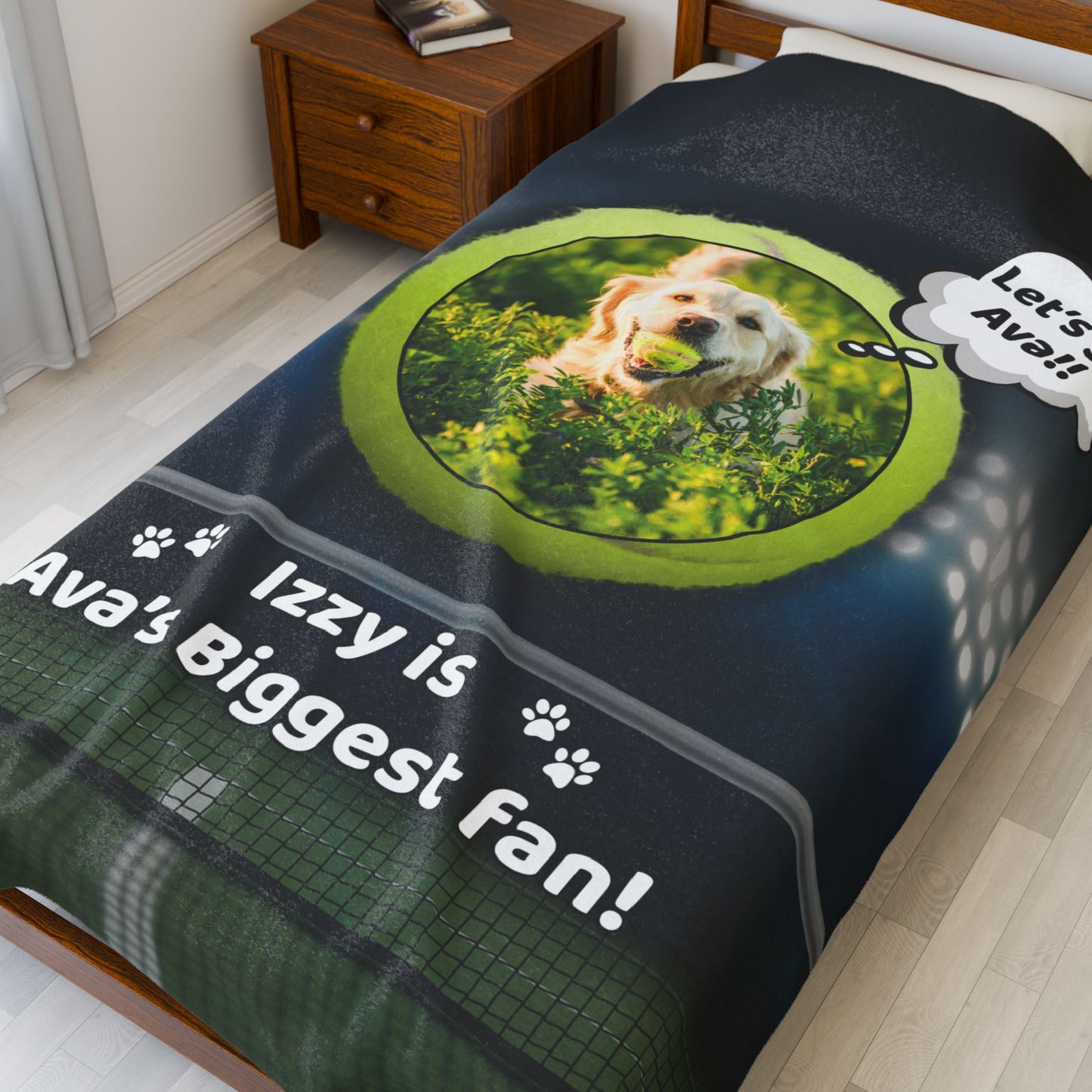 Custom tennis-themed blanket displayed on a bed, featuring a happy golden retriever with a tennis ball and the phrase “Izzy is Ava’s Biggest Fan!” in bold white text, with a stadium light background and tennis net graphic.
