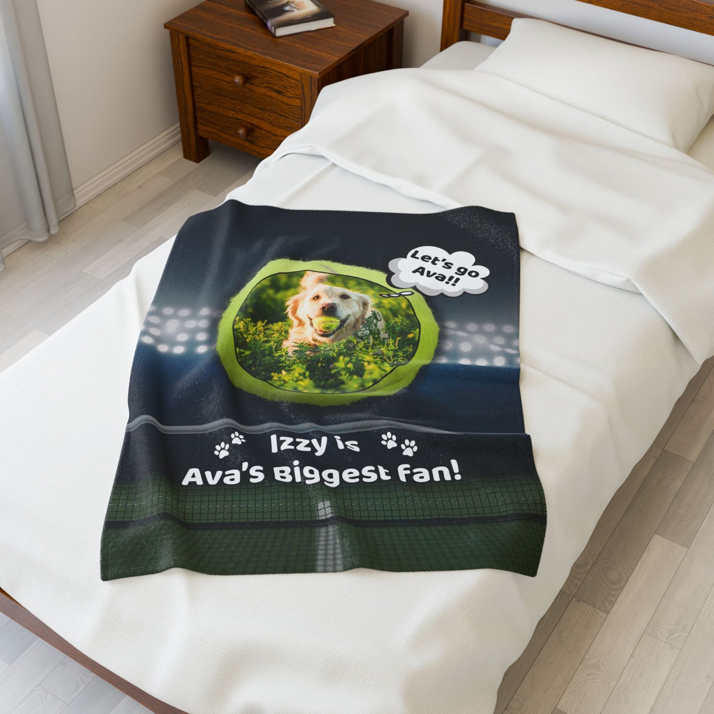 Personalized tennis-themed blanket laid on a white bed, showing a golden retriever with a tennis ball and the text “Izzy is Ava’s Biggest Fan!” beneath stadium lights and a court backdrop.