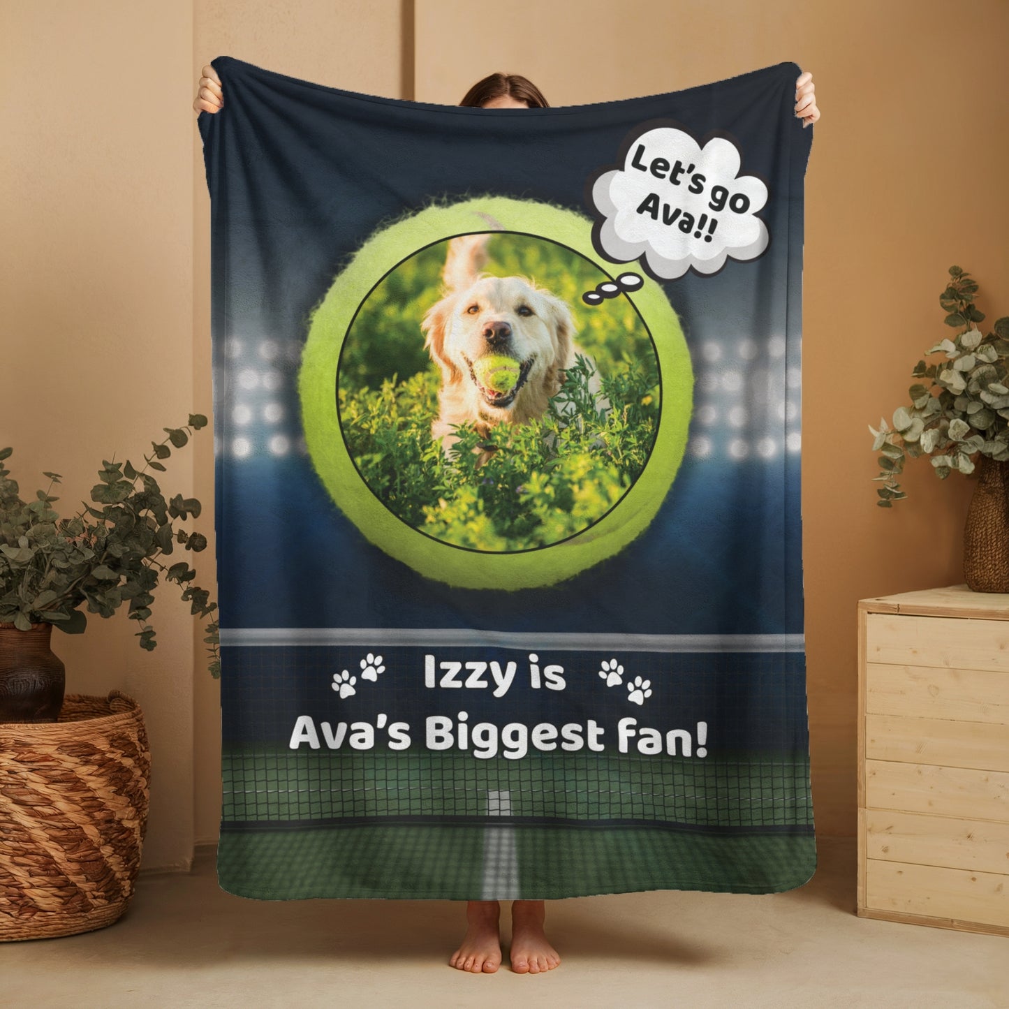 Personalized tennis-themed blanket laid on a white bed, showing a golden retriever with a tennis ball and the text “Izzy is Ava’s Biggest Fan!” beneath stadium lights and a court backdrop.