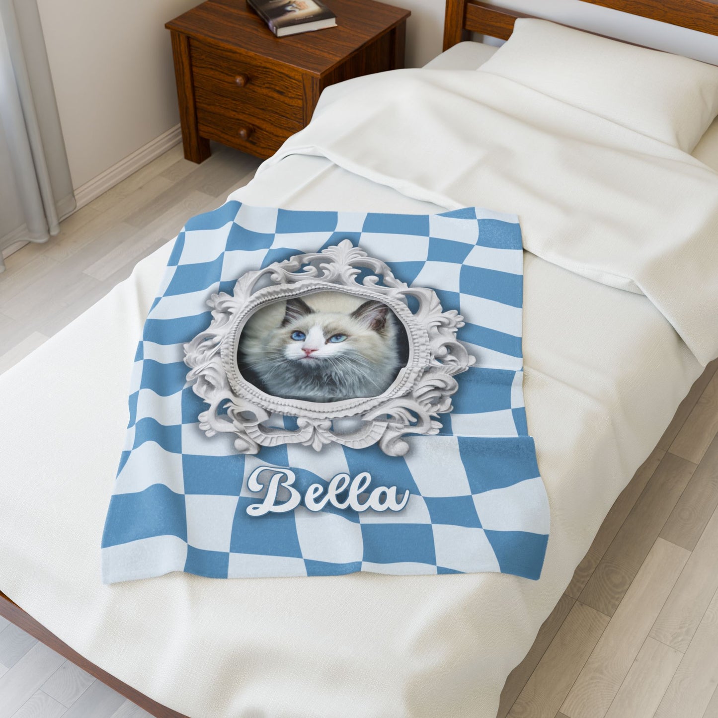 Personalized cat blanket with name Bella and elegant white frame featuring pet photo, displayed folded on a white bed