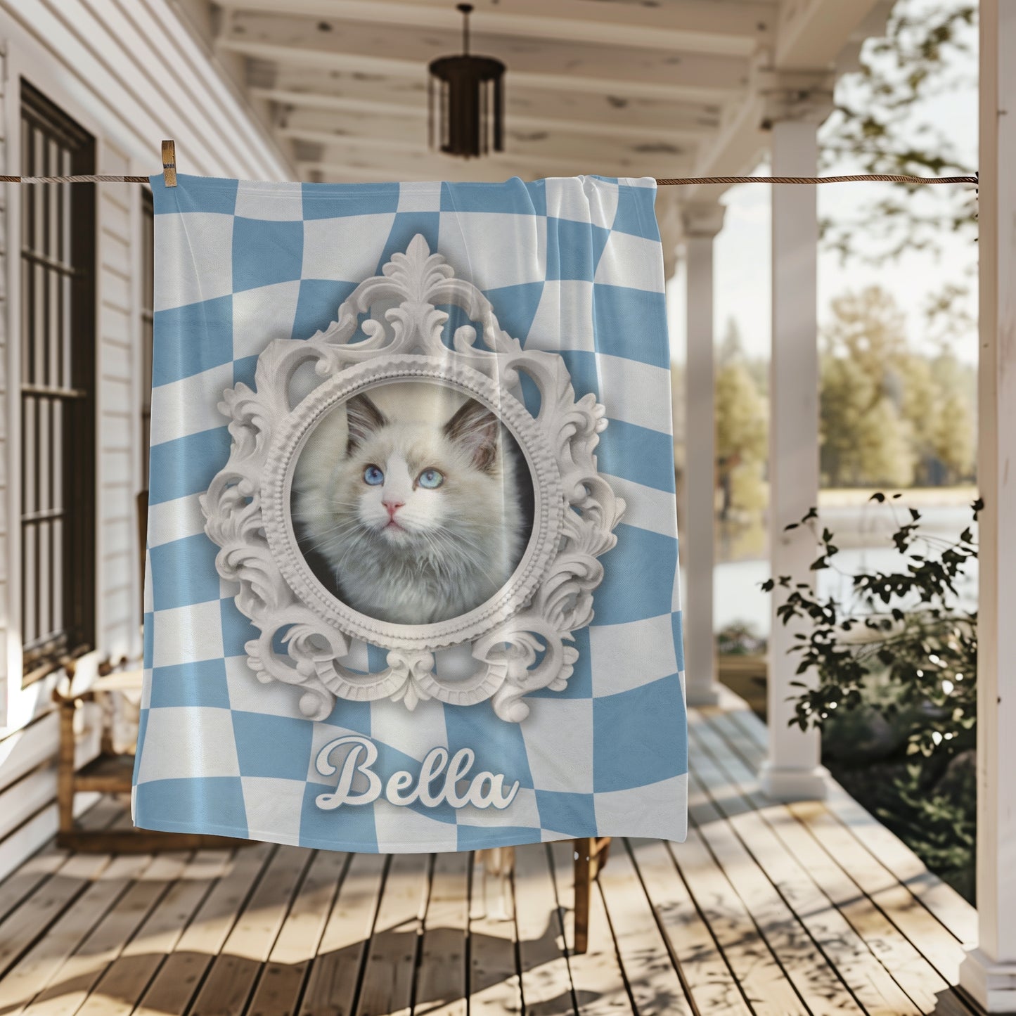 Personalized cat blanket with name Bella and ornate white frame, hanging outdoors on a farmhouse porch railing