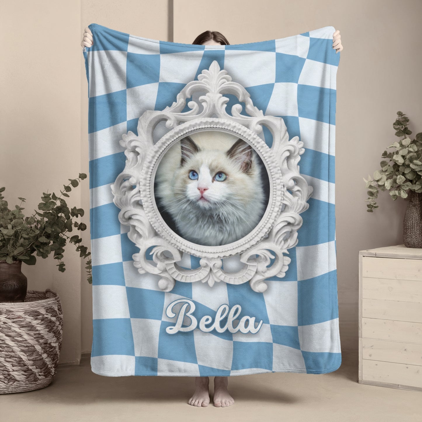 Personalized cat photo blanket featuring blue and white checkered background, ornate frame, and name Bella, held up by person indoors