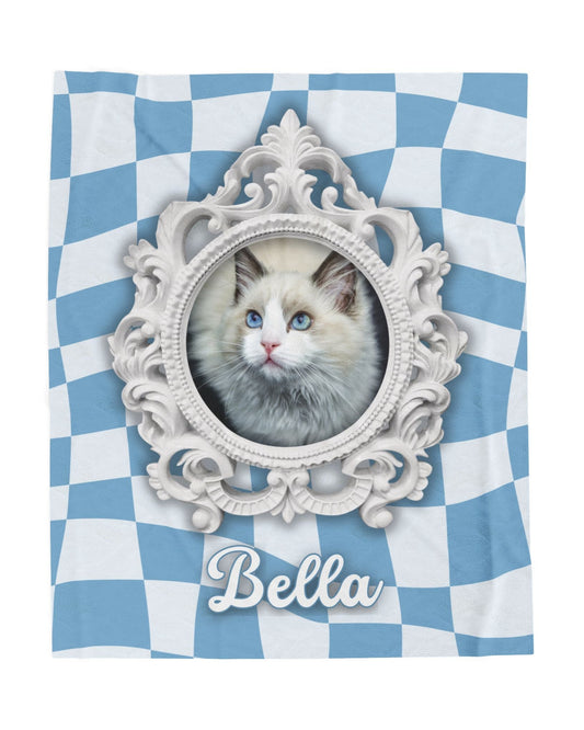 Flat image of personalized cat blanket featuring ornate white frame, photo of cat, and pet name on blue and white checkered background