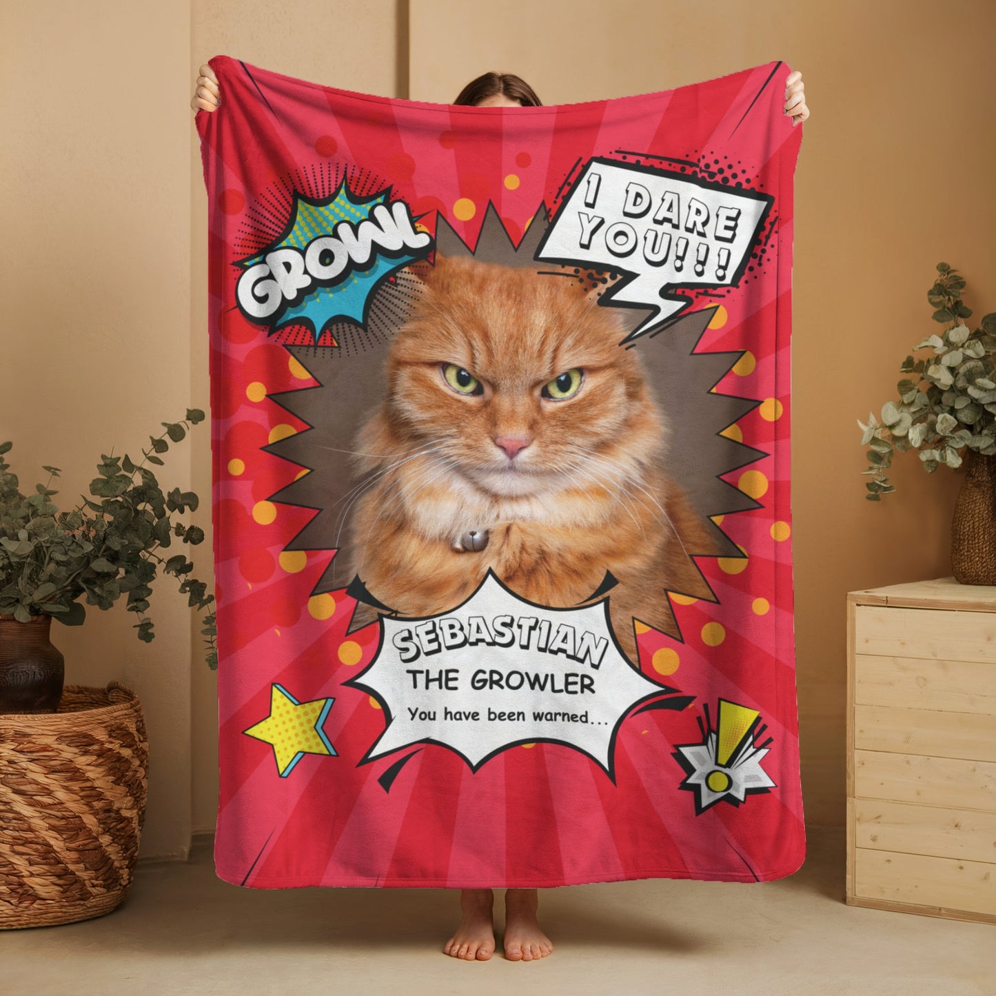 Person holding up a personalized comic-style cat blanket featuring an orange tabby named Sebastian with “Growl” and “I Dare You” speech bubbles on a red background