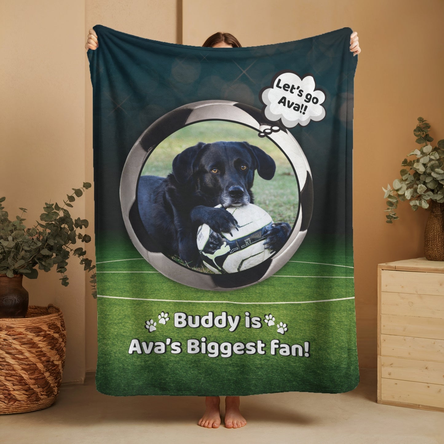 Personalized soccer dog blanket featuring Buddy and “Ava’s Biggest Fan” message, held up in a warm home setting to show full blanket size and detail