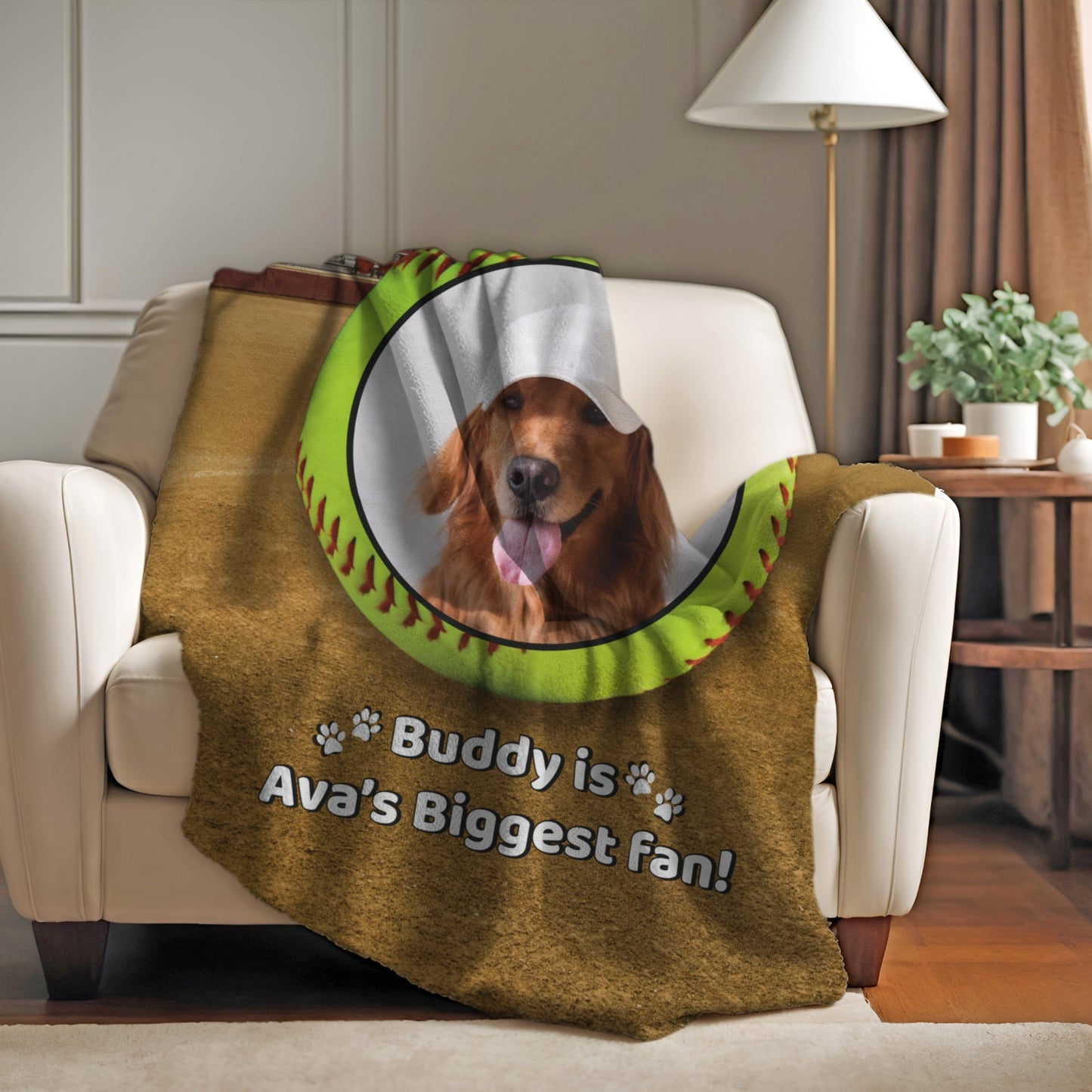 Personalized softball dog blanket featuring Buddy and the phrase “Buddy is Ava’s Biggest Fan,” draped over a cozy white couch in a warm living room setting