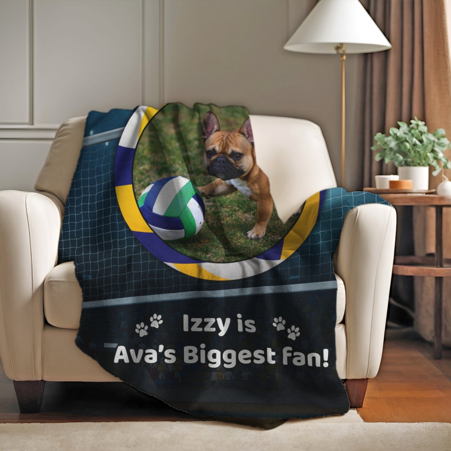 Custom volleyball blanket with Izzy the French Bulldog draped over a cozy armchair in a warm, softly lit living room.