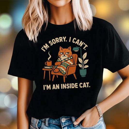 Woman wearing black t-shirt with “I’m Sorry, I Can’t, I’m an Inside Cat” graphic design featuring orange cat wrapped in blanket with coffee and plant, cozy retro style.