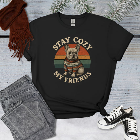 Black t-shirt with a dog graphic and text 'Stay Cozy My Friends' on a wooden surface with jeans and sneakers.