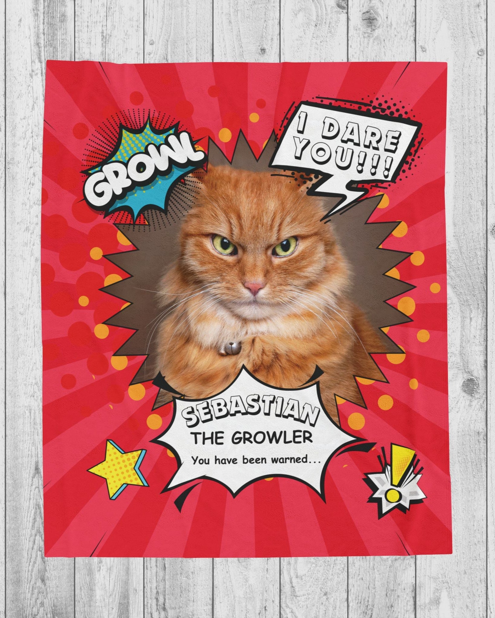 Flat lay of personalized comic-style cat blanket featuring an orange tabby named Sebastian with speech bubbles and a red background on a wood floor