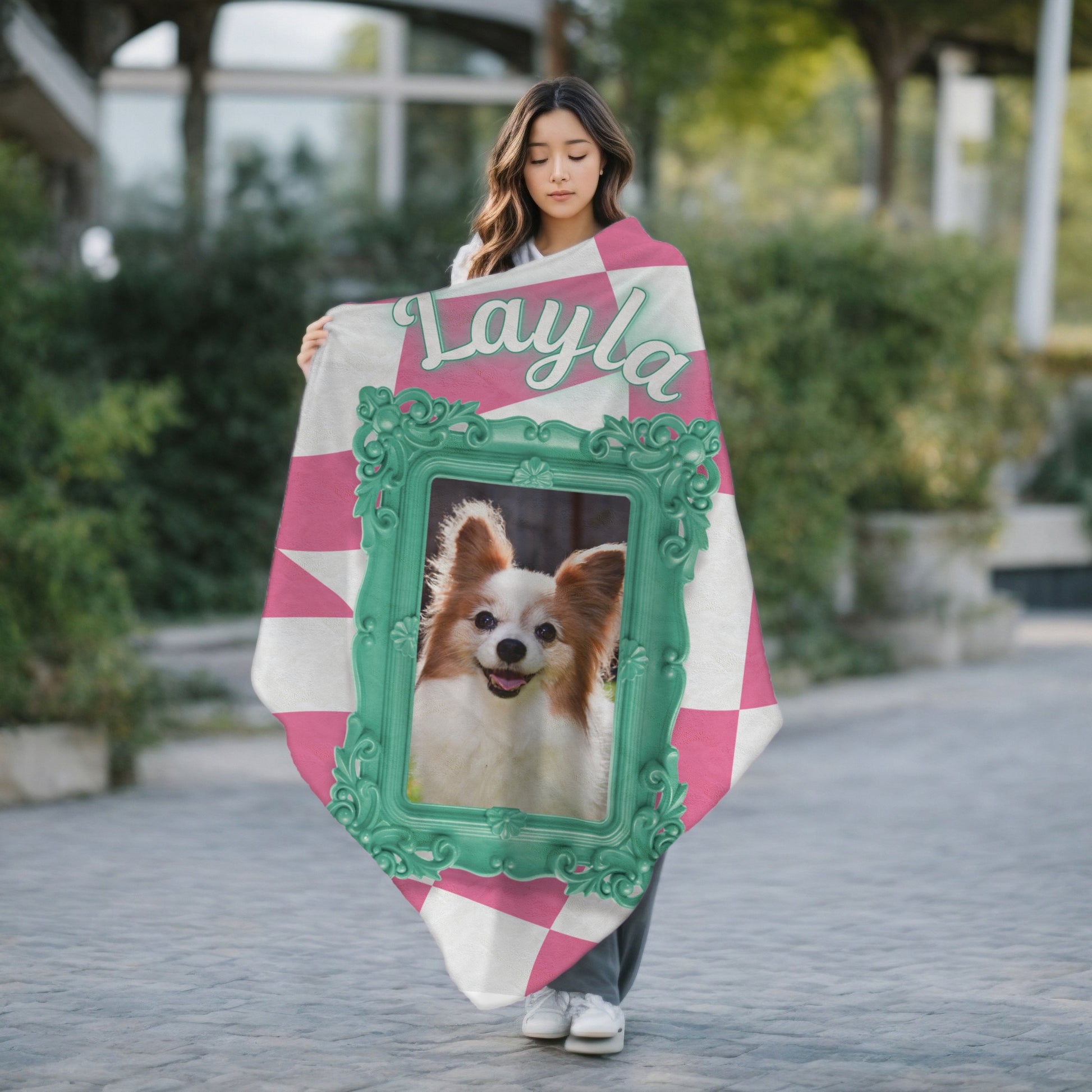 Personalized dog blanket with photo and name Layla, pink checkered pattern and teal frame, shown outdoors with woman holding it