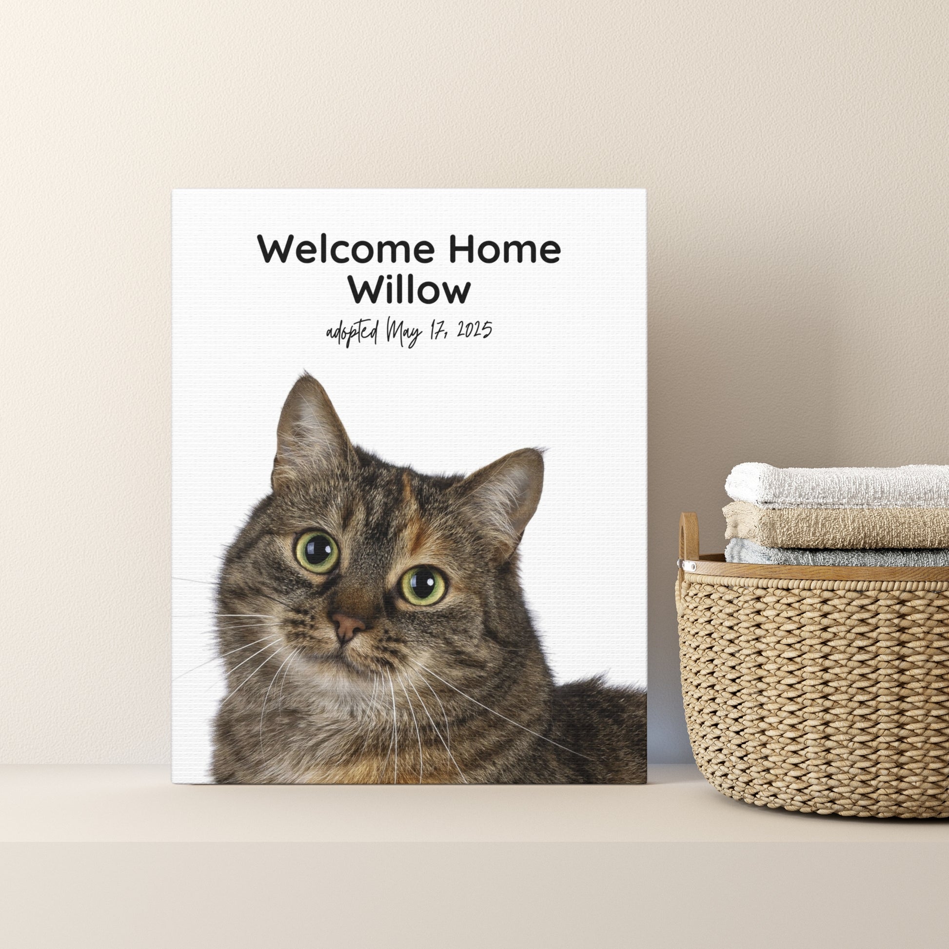 Custom “Welcome Home Willow” canvas with adoption date, shown on a bathroom shelf next to a wicker basket and folded towels.