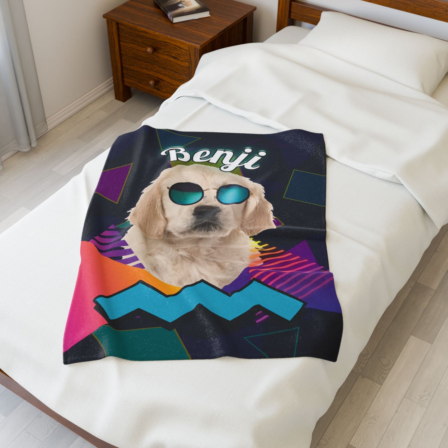 Personalized retro dog blanket with neon shapes and pet name Benji, folded on a white bed with nightstand in the background