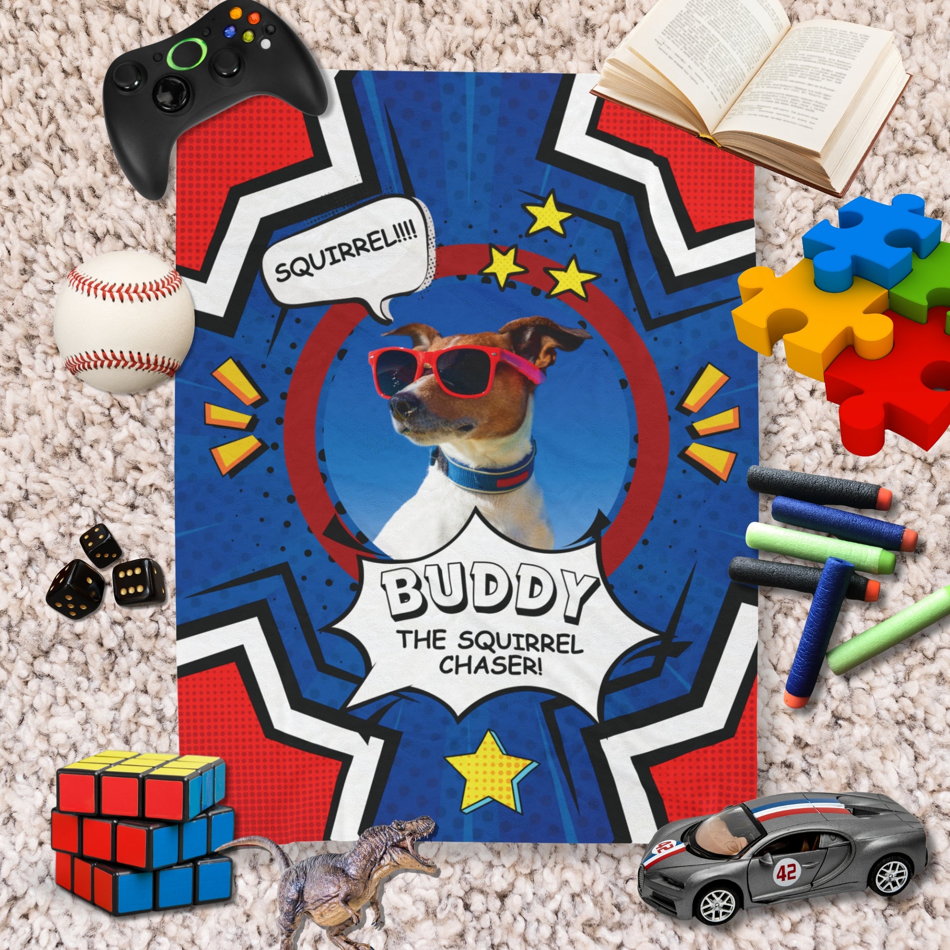 Comic-style custom dog blanket with Buddy wearing red sunglasses and “Squirrel Chaser” title, surrounded by kids’ toys on carpet including blocks, cars, and Nerf darts